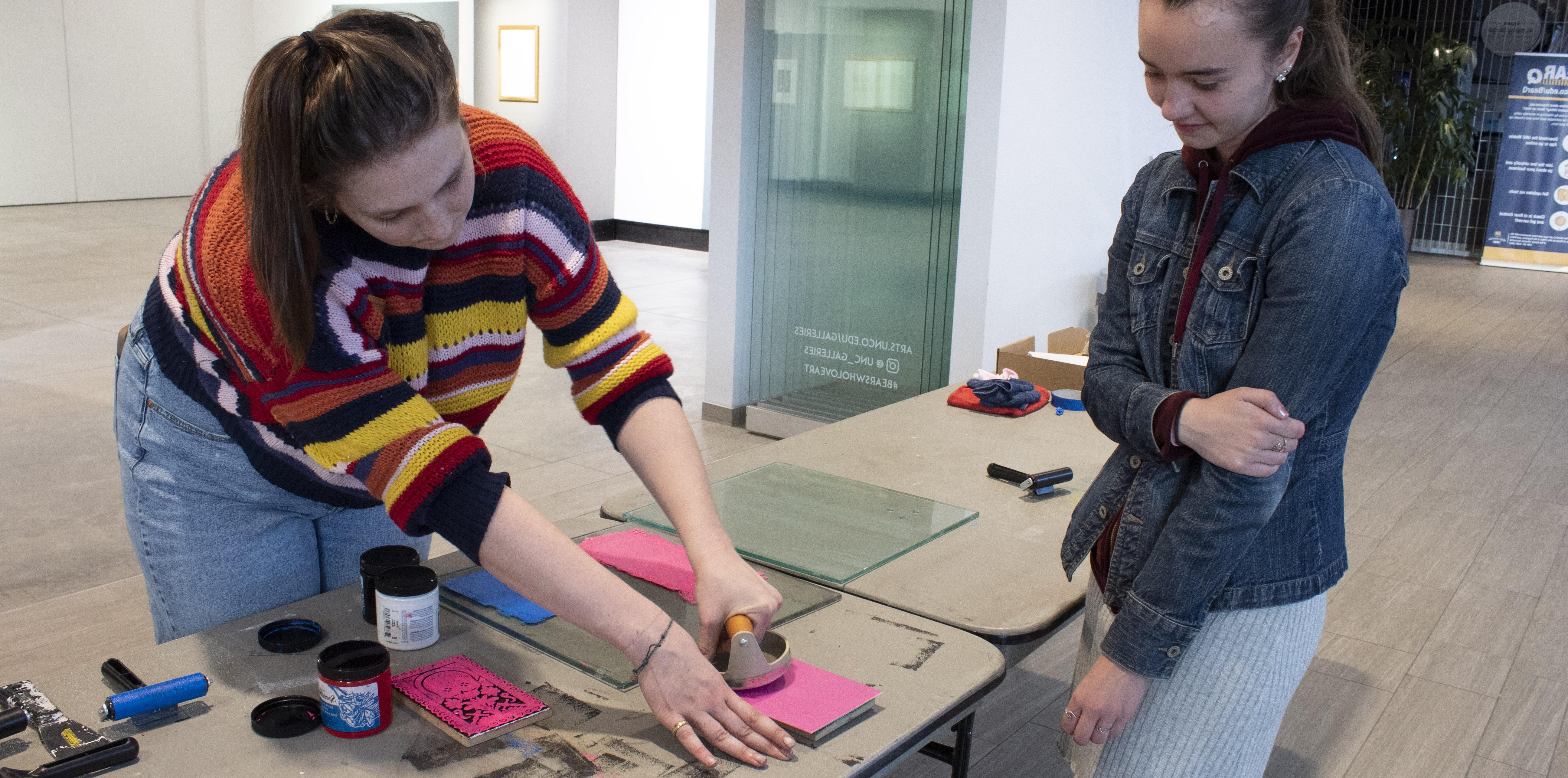 凯瑟琳·卡明斯 帮助参与者制作木版印刷卡片 by showing them the process it takes to make a block print.