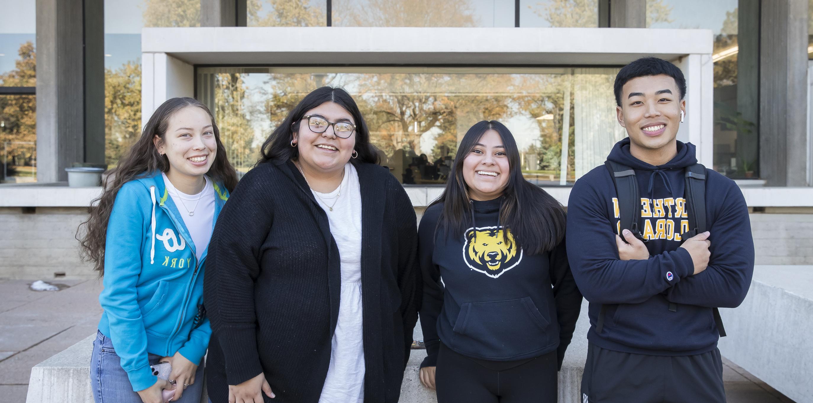 Four college students standing together outside smiling